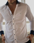Diseño que desafía lo convencional. Esta camisa fusiona lo clásico y lo contemporáneo con un juego visual de rayas azul marino y blanco, contrastadas por un panel sólido en blanco puro.